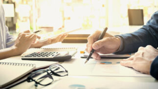 Two people working on financial statements across a desk.