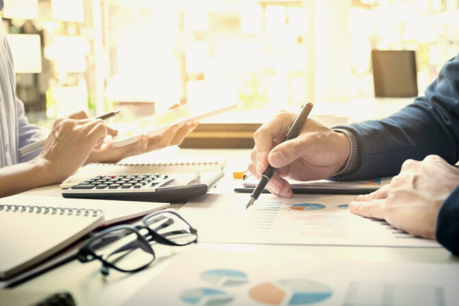 Two people working on financial statements across a desk.