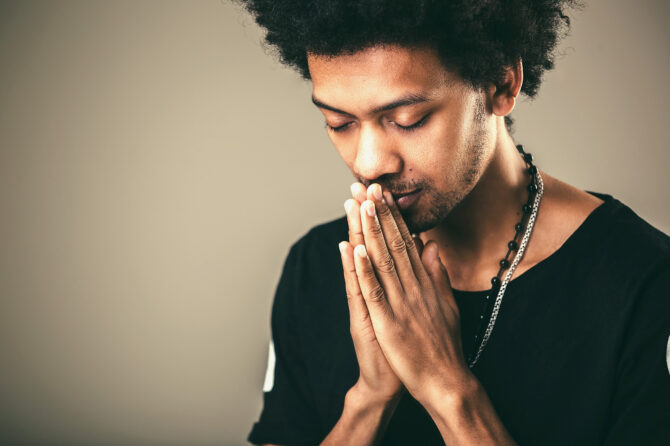 Person holding their hands in front of their face as if in prayer.