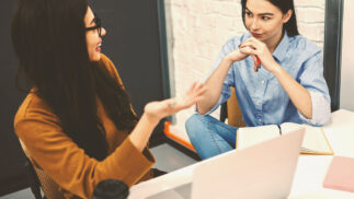 Two young business people in a discussion at a desk.