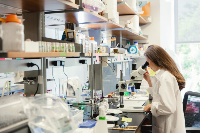 Scientist in a biology lab using a microscope.