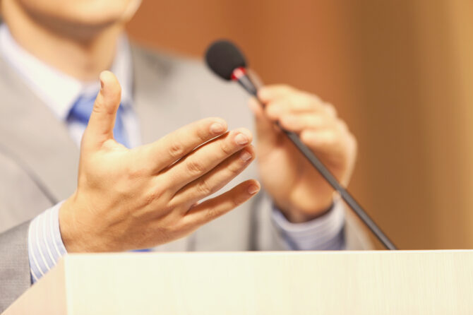 Man wearing a suit speaking at a podium.