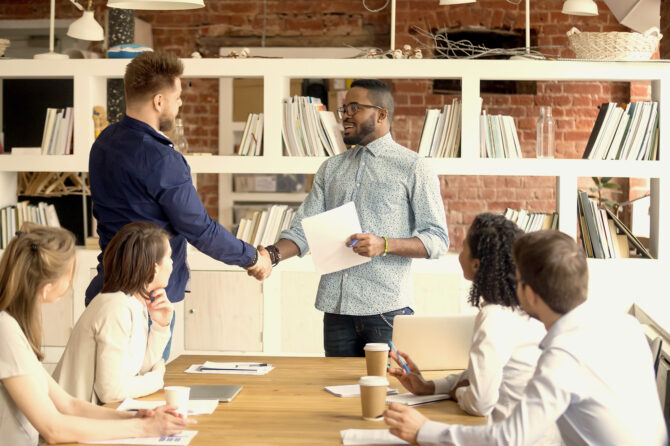 Young professionals closing a financial deal with a handshake.