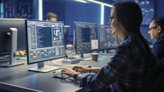 Room of computer specialists reviewing information on monitors.