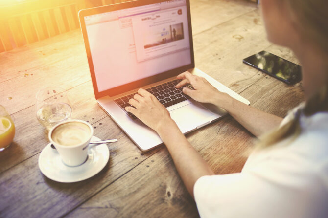 Person creating content on a notebook computer in a coffee shop.