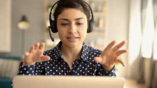 Programmer gesturing at a computer while wearing headset.