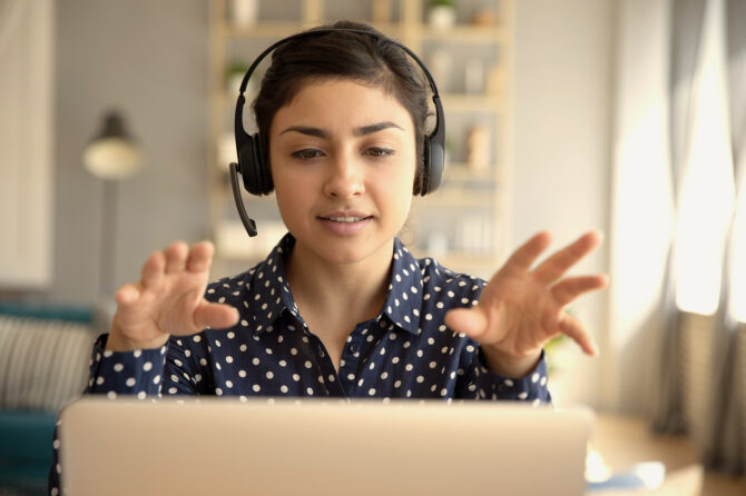 Programmer gesturing at a computer while wearing headset.