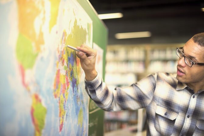 Person identifying important places on a world map.