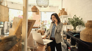 Small business owner working on a computer and speaking on the phone in a store.