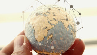 Hand holding a small globe with superimposed network showing connections.