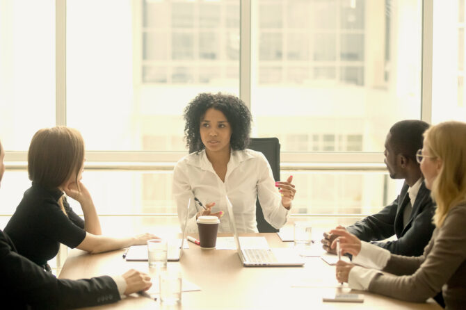 Young executive leading a team at a board room table.