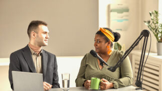 Two journalists having a discussion in front of a microphone.