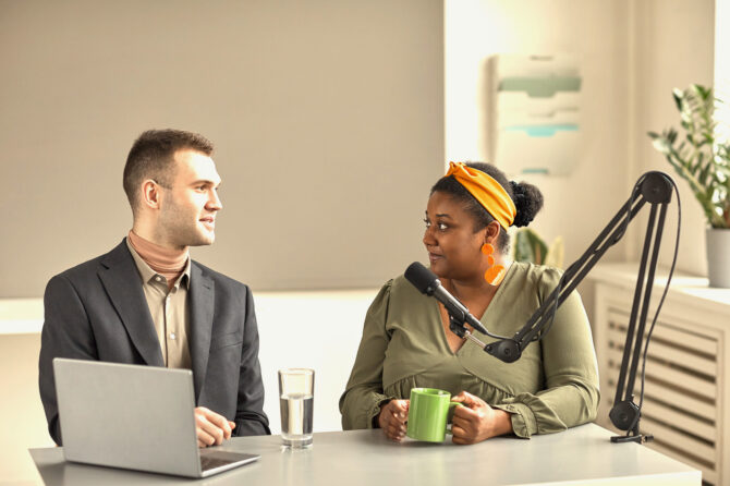 Two journalists having a discussion in front of a microphone.