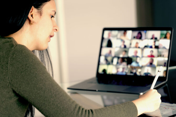 A woman takes notes while in a virtual class.