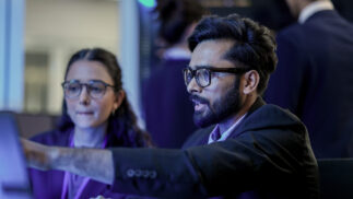 Cybersecurity professionals indicating to a computer.