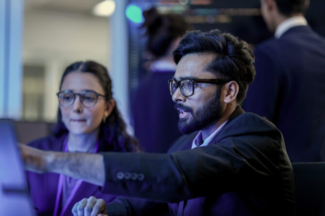 Cybersecurity professionals indicating to a computer.